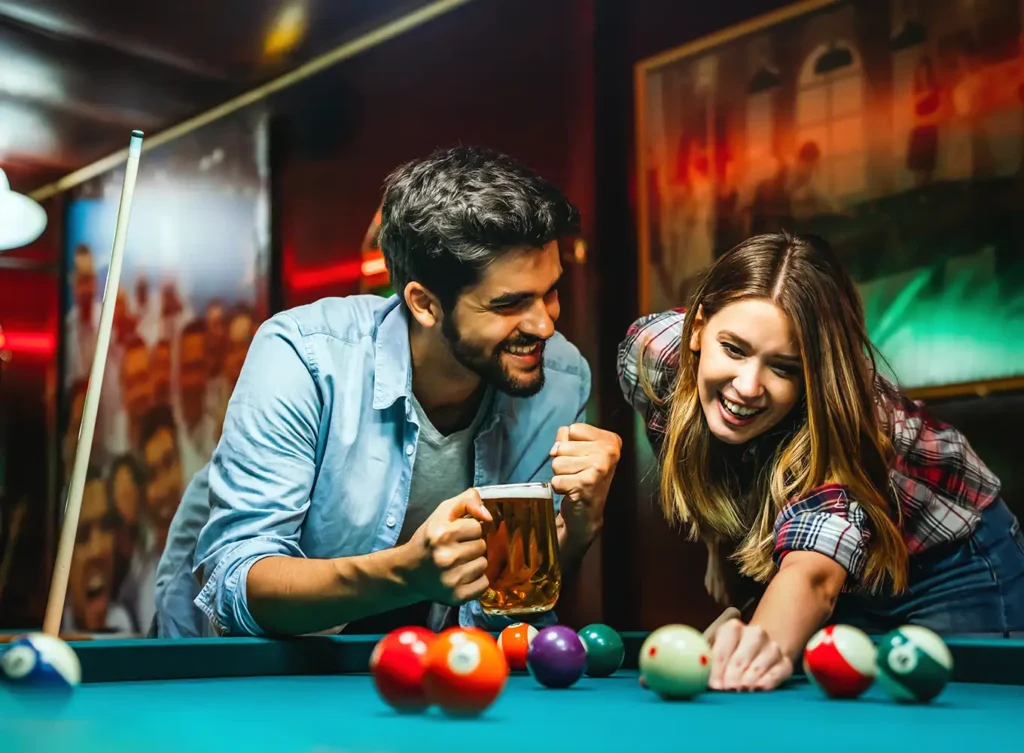 2 people playing pool at a bar